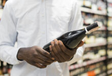 man inspecting bottle wine alcohol section