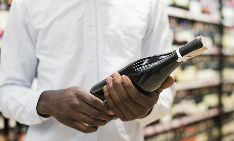 man inspecting bottle wine alcohol section