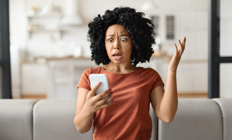oh no shocked black woman reading bad message smartphone home scaled